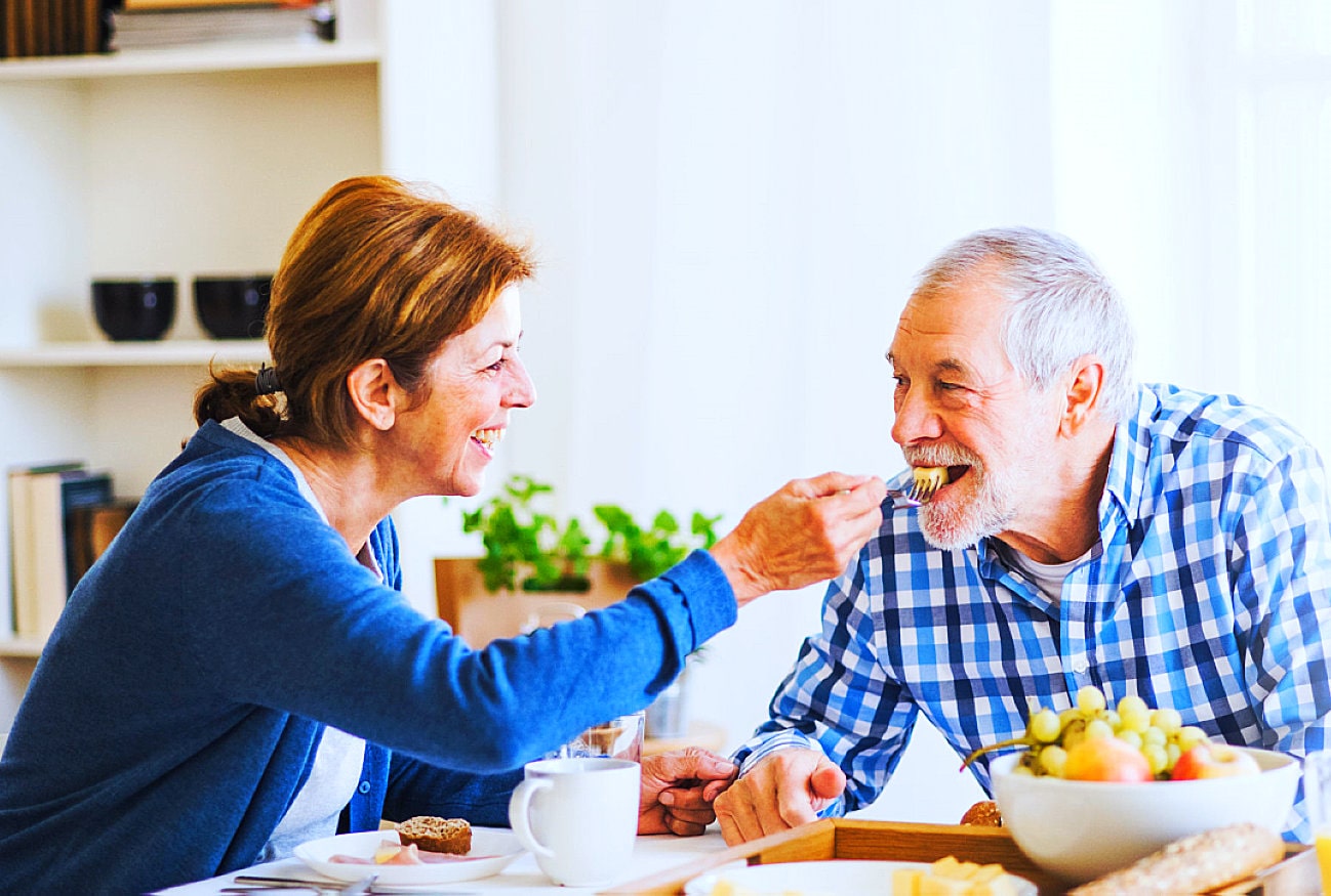 senior woman feeding senior man